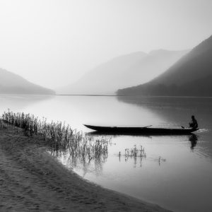 Black and white photography artwork of boat, river, human, and hills