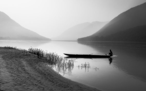 Black and white photography artwork of boat, river, human, and hills